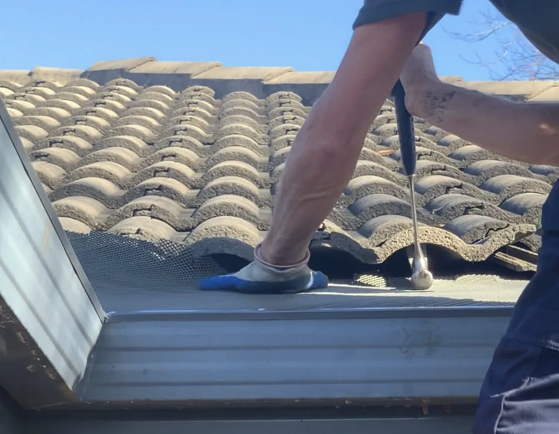 Gutter guard being fitted to a concrete tile roof